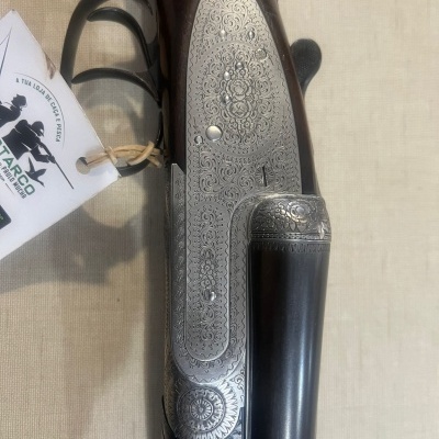 Espingarda com detalhes em metal gravado e madeira escura sobre tecido bege