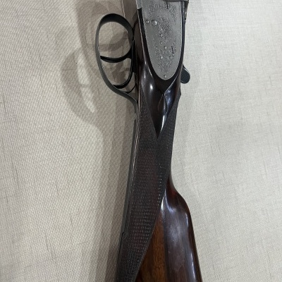 Espingarda de canos duplos com empunhadura de madeira escura e partes metálicas prateadas