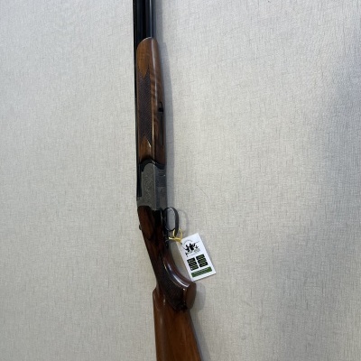 Espingarda de canos duplos com coronha de madeira e canos negros pendurada na parede