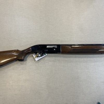 Espingarda com madeira castanho escuro e metal preto, sobre tecido cinza claro