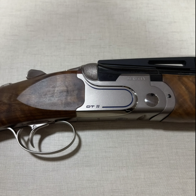 Espingarda de cano duplo com empunhadura em madeira escura e detalhes metálicos