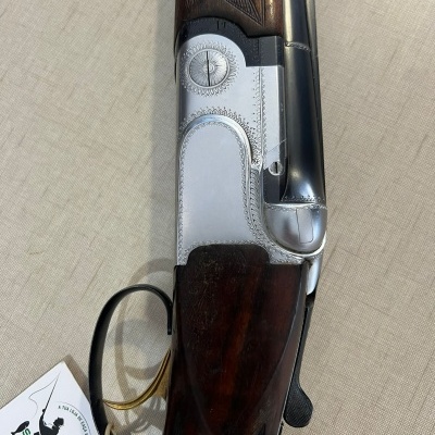 Espingarda de canos duplos com madeira escura e metal prateado gravado