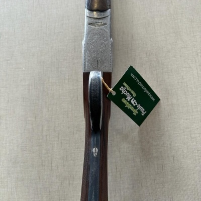 Espingarda de caça com coronha em madeira castanha e metal gravado, etiqueta verde pendurada