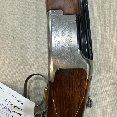 Espingarda de caça em madeira castanha e metal prateado com etiqueta branca pendurada