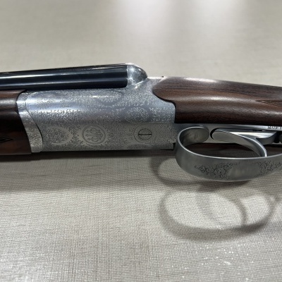 Espingarda de canos paralelos com punho em madeira e partes metálicas gravadas