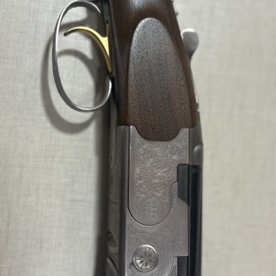 Espingarda Beretta com cabo de madeira e detalhes metálicos gravados