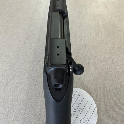 Espingarda preta com etiqueta branca redonda e texto manuscrito