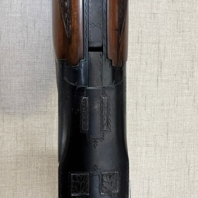 Parte superior de espingarda de madeira e metal com decoração gravada