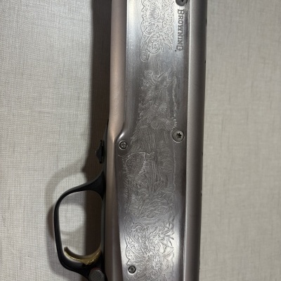 Peça de espingarda metálica gravada com texto BROWNING e gatilho dourado