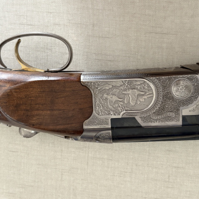 Espingarda com punho em madeira castanha e caixa de metal com gravações e texto Beretta.