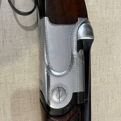 Espingarda de madeira escura com detalhes em metal prateado e gravações detalhadas