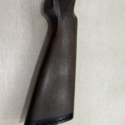 Coronha de arma de fogo em madeira escura com padrão quadriculado para aderência e calcanhar preto ventilado