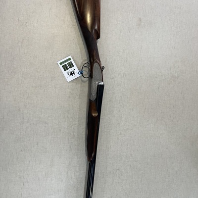 Espingarda de canos duplos com coronha em madeira escura e etiqueta pendurada