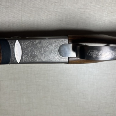 Espingarda com coronha de madeira escura e corpo metálico gravado