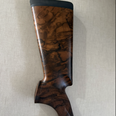 Parte traseira da coronha de um rifle em madeira castanha com textura natural