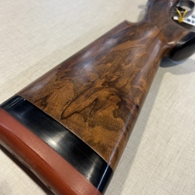 Coronha de arma em madeira castanha, ponteira vermelha e detalhe preto