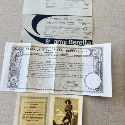 Documentos sobre armas Beretta em tecido bege.