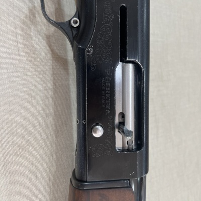 Detalhe de arma de fogo preta com madeira e texto gravado