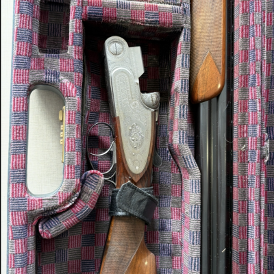 Espingarda de canos duplos em mala quadriculada vermelha, cinza e azul