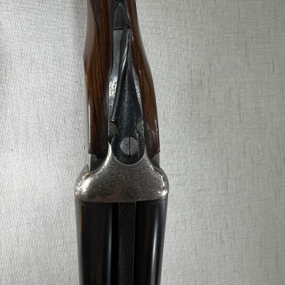 Espingarda de canos duplos com empunhadura em madeira e metal gravado.