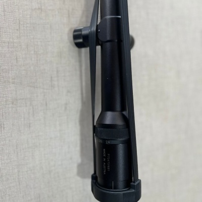 Mira telescópica preta montada numa arma com texto visível