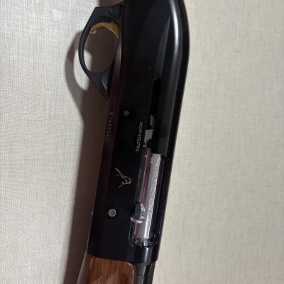 Espingarda com empunhadura em madeira e corpo preto com texto MONTEFELTRO e Benelli Inertia System