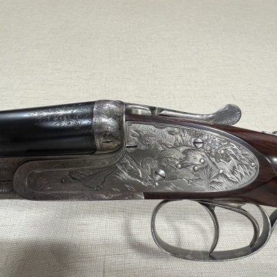 Arma de caça de cano duplo com detalhes gravados e cabo em madeira castanha