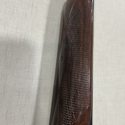 parte frontal de arma com madeira castanha e cano metálico preto