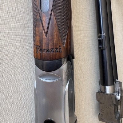 Parte de uma arma de caça Perazzi com madeira castanha e metal prateado