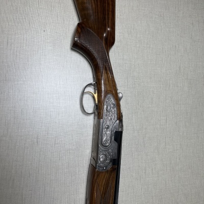 espingarda de caça com madeira escura e acabamento metálico gravado