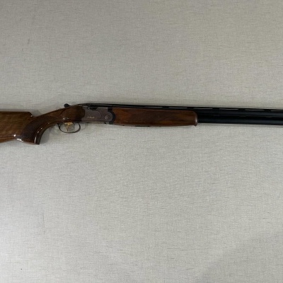 Espingarda de canos paralelos com madeira castanha e metal preto sobre fundo neutro