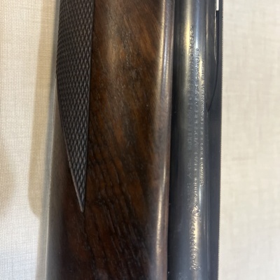 Parte de uma arma de fogo com madeira texturizada e metal gravado