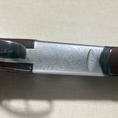 Detalhe de caçadeira Beretta com gravações e madeira castanha escura