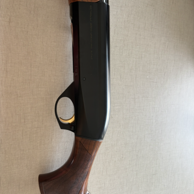 Espingarda com cabo e coronha em madeira castanha e corpo em metal preto com texto gravado.