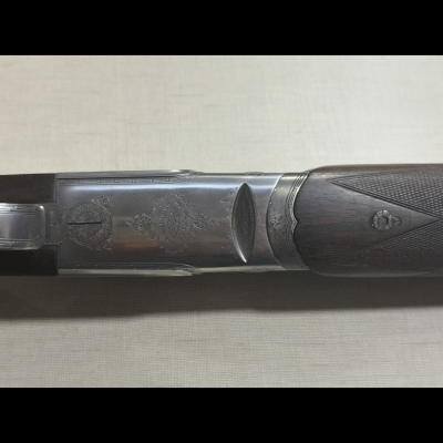 Espingarda com coronha de madeira e detalhes gravados no metal.