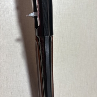 Detalhe de espingarda com metal preto e madeira castanha, gravação BROWNING no metal.