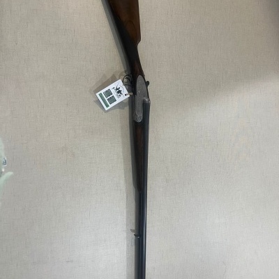 Espingarda de cano duplo com coronha em madeira escura e detalhes metálicos prateados