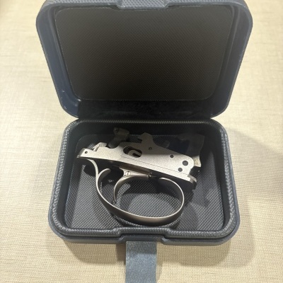 Mecanismo de arma dentro de caixa azul aberta em superfície bege.