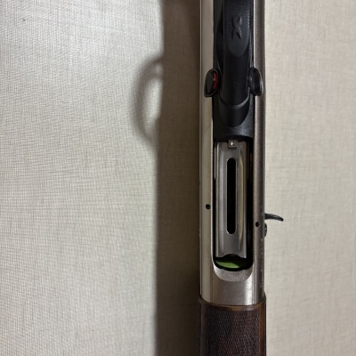 Espingarda de caça com madeira escura e corpo metálico prateado