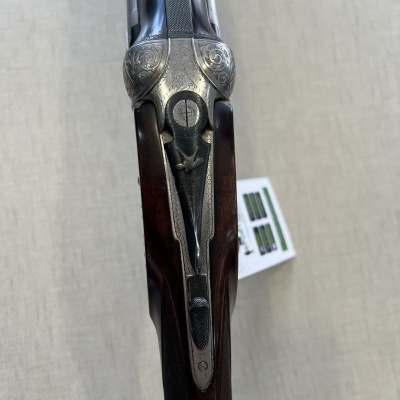 Espingarda com coronha de madeira e gravações em metal prateado vista de cima