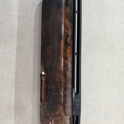 Coronha de espingarda em madeira castanha escura com padrão texturizado e tubo metálico preto