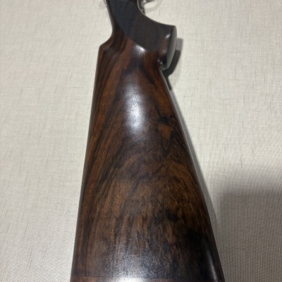 Coronha de madeira escura de arma de fogo sobre tecido bege claro