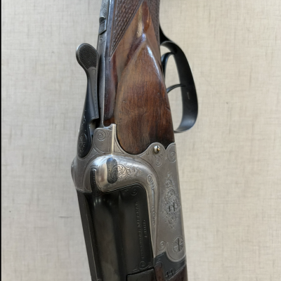 Espingarda de caça em madeira e metal com gravações e texto.