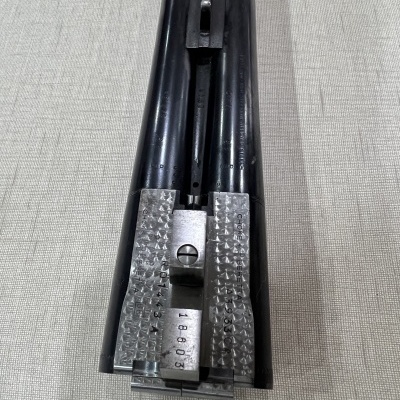 Parte frontal de arma de canos duplos em metal preto com peças metálicas prateadas na base