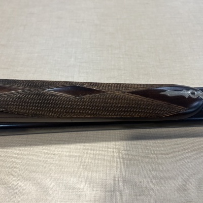 Punho de madeira texturizada e metal prateado sobre superfície clara