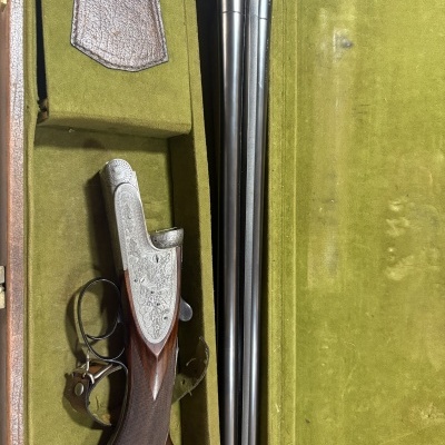 Espingarda de caça de canos duplos em estojo verde de veludo