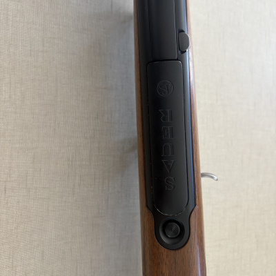 Parte superior de arma de fogo com madeira e metal preto com texto SAUER