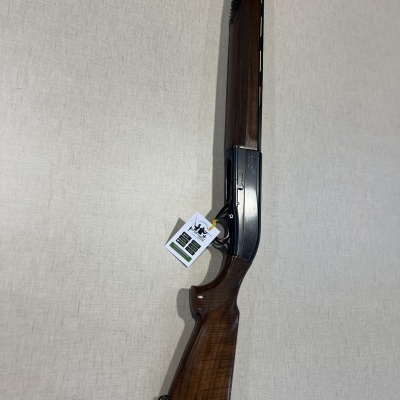 Espingarda com madeira castanha e cano preto pendurada na parede