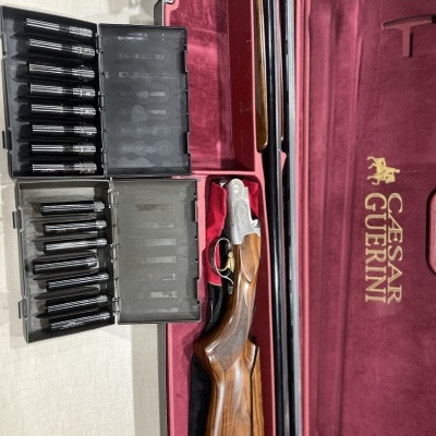 Espingarda desmontada em estojo vermelho com cartuchos em estojos pretos