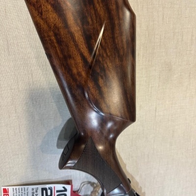 Espingarda com coronha em madeira castanha polida e parte superior preta com inscrições douradas.